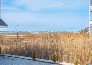 A coastal view with a building, a sandy beach, and a distant marina. - Bayview Condo Short Walk to Beach (Ocean City)