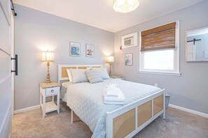 A bedroom with a bed, bedside tables, wall-mounted air conditioning, and a window with a blind. - Bayview Condo Short Walk to Beach (Ocean City)