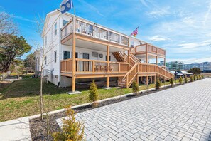 A multi-story building with a wooden deck, a flag, and a staircase. - Bayview Condo Short Walk to Beach (Ocean City)