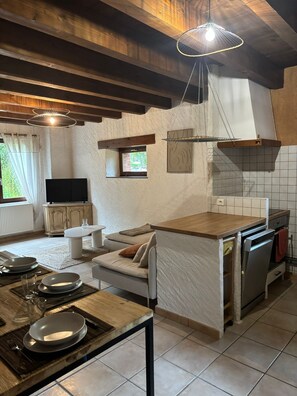 Une cuisine dotée d’un plan de travail en bois, d’un four encastré et d’un coin repas avec un canapé et un téléviseur.