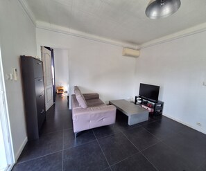 Ein modernes Wohnzimmer mit einer Couch, einem Couchtisch, einem Fernseher auf einem Schrank und einem Kleiderschrank.