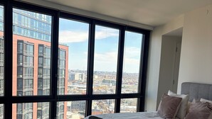 A bedroom with a large window, a bed, and a view of a cityscape. - 2-bedroom apartment in Greenpoint Brooklyn with stunning views (Brooklyn)