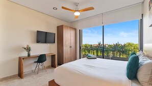 Ein Schlafzimmer mit Bett, Schreibtisch, Stuhl, Fernseher und Deckenventilator.