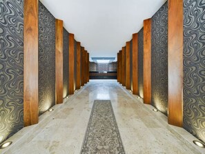 A corridor with patterned walls and wooden columns, leading to a reception area. - 3 BR Tulum Penthouse Private Pool & Stunning Views, Fast Internet, Work Area (tulum)