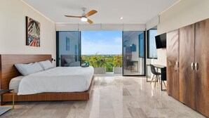 Ein modernes Schlafzimmer mit Bett, Deckenventilator, Fernseher und Blick ins Freie.