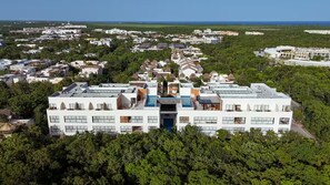 Ett modernt hotellkomplex med flera byggnader, omgivet av frodig grönska och med en fantastisk utsikt över havet.