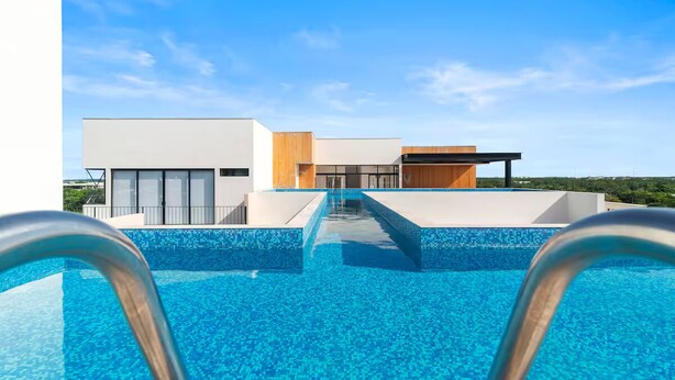 Ein modernes Hotel mit Swimmingpool, blauem Himmel und Blick auf die umliegende Landschaft.
