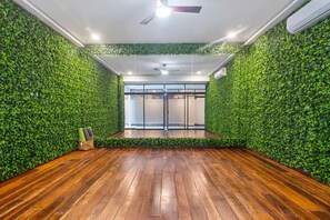 A room with a wooden floor, green foliage walls, a ceiling fan, and a view of a glass door. - 3 BR Tulum Penthouse Private Pool & Stunning Views, Fast Internet, Work Area (tulum)