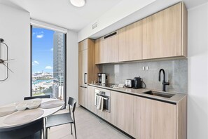 A modern kitchen with a large window, a dining area with a table and chairs, and a view of a cityscape. - Near FIFA Fan Fest | Spacious 2BR | Free Parking (Miami)