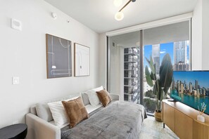 A modern bedroom with a large bed, a TV, and a balcony with a city view. - 2BR | FIFA Fan Fest 15-Min Walk | Free Parking (Miami)