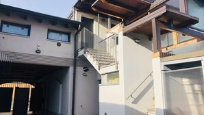 Ein modernes, zweistöckiges Gebäude mit einer überdachten Garage, einem Balkon und einer Treppe.