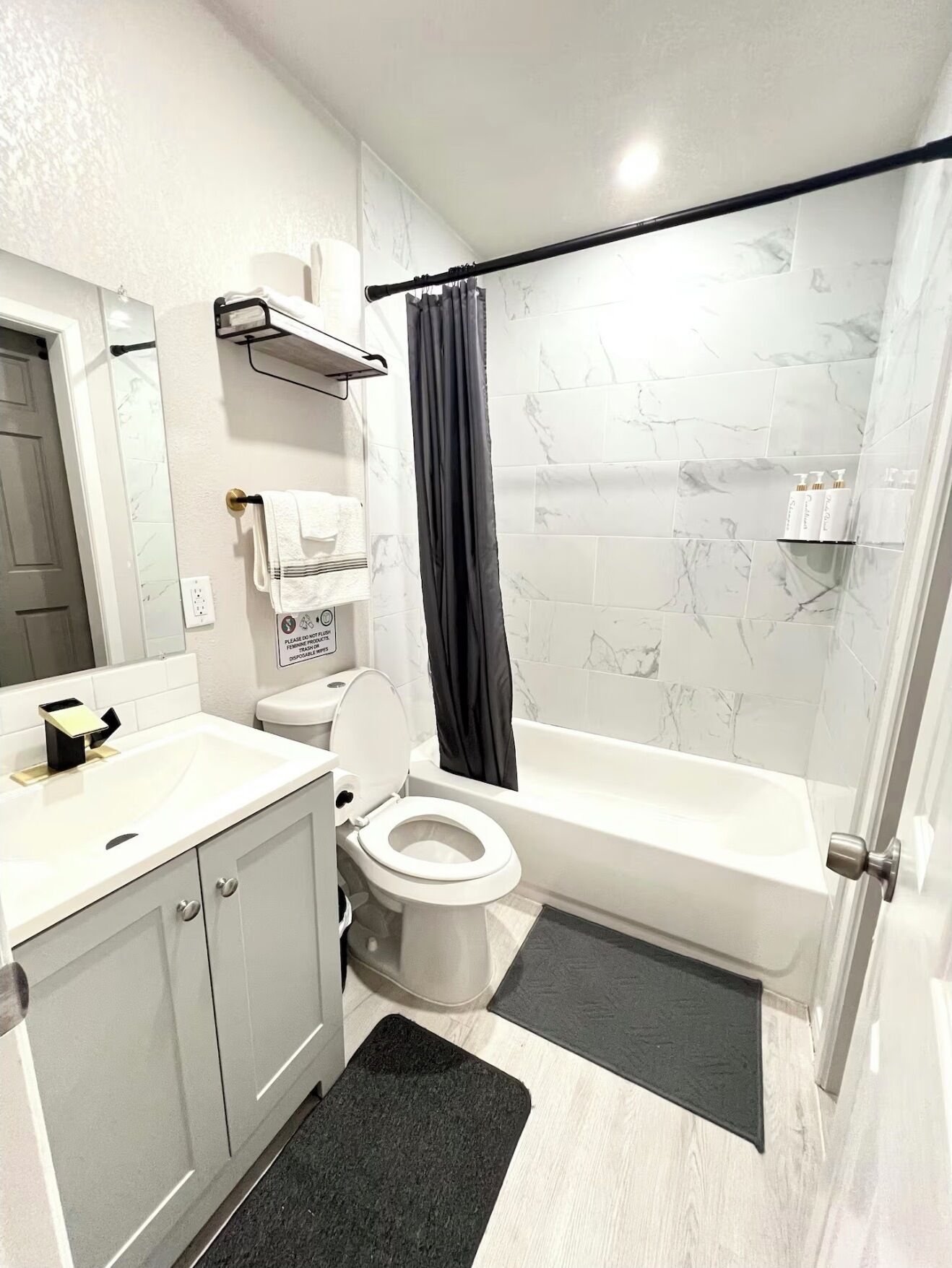 Ein Badezimmer mit Toilette, Waschbecken, Spiegel und Badewanne.