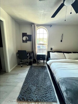 A bedroom with a bed, a desk, a chair, a ceiling fan, and a window. - Furnished 3-bedroom house near downtown Dallas (Dallas)