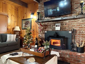 Una sala de estar acogedora con chimenea, televisor, árbol de Navidad y una mesa de centro de madera.