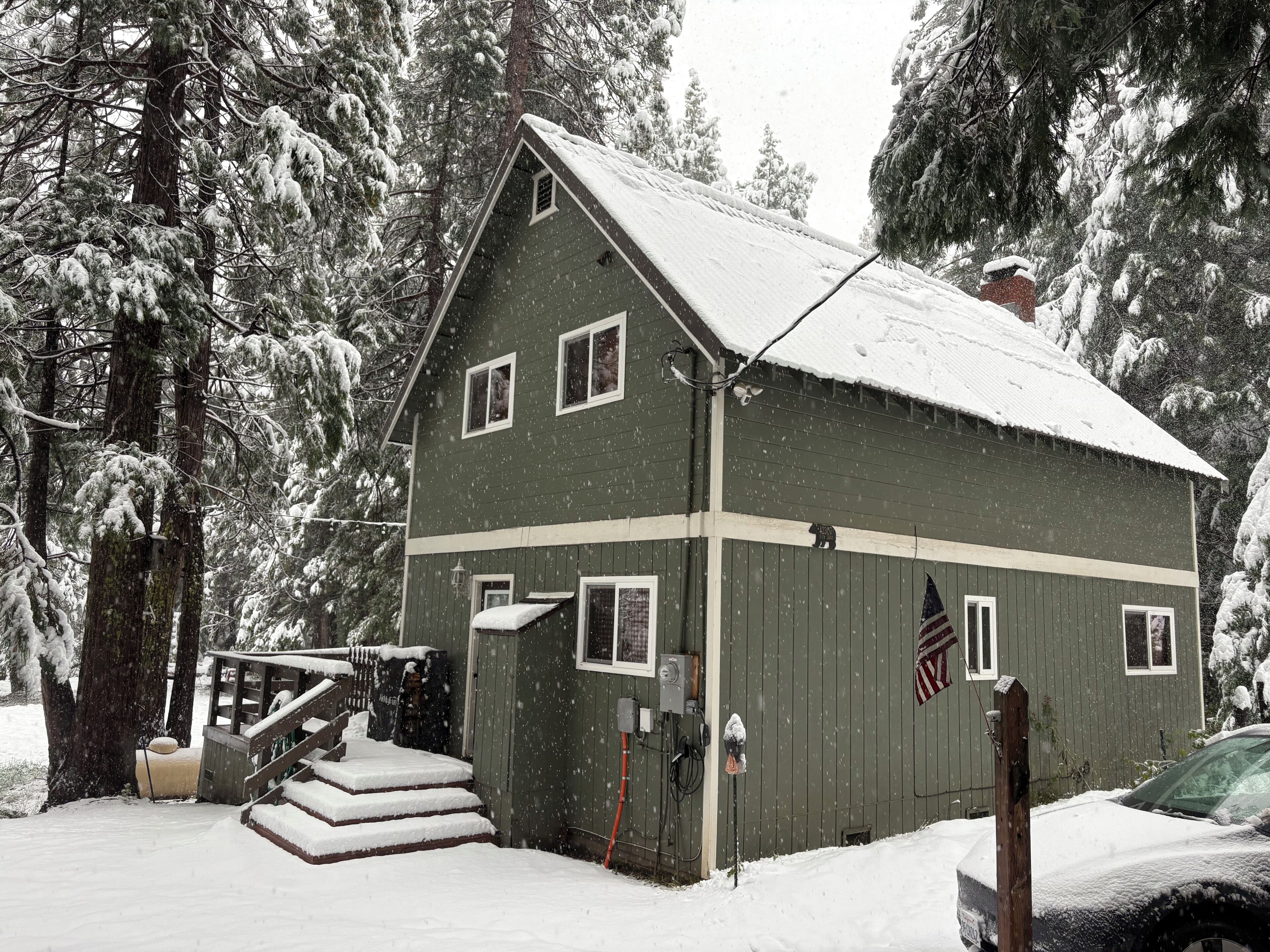 A two-story building with a snow-covered roof, surrounded by snow-laden trees.