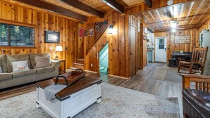 Ein Holzinnenraum mit einer Couch, einem Couchtisch, einer Treppe und einem Essbereich.