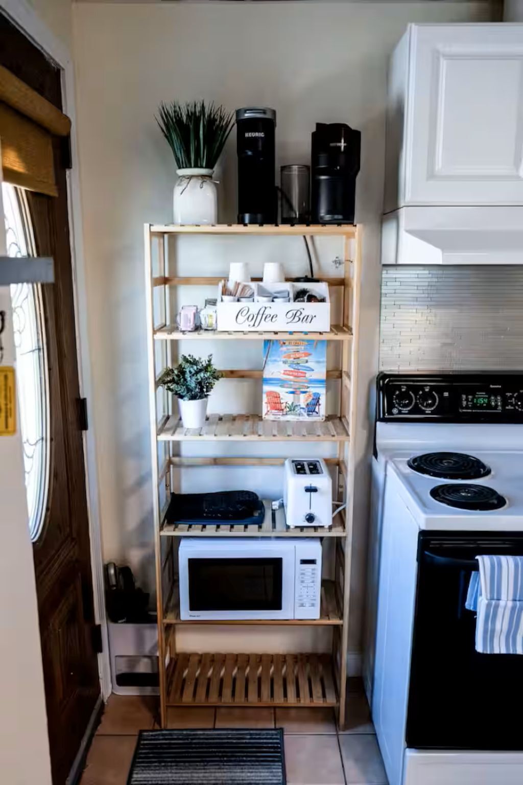 Een keuken met een koffiebarretje, een magnetron, een broodrooster en een fornuis.
