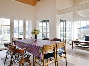 A dining area with a table set for four, surrounded by wooden chairs with patterned cushions.