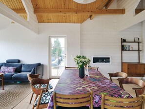 A dining area with a long table, chairs, a vase with flowers, and a bookshelf. - 4 Star Holiday Home in Korsor (Korsor)