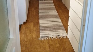 A hallway with wooden flooring, a patterned rug, white walls, and a dark wooden door at the end. - 2 Bedroomapartment in Danderyd, City Stay (Danderyd)