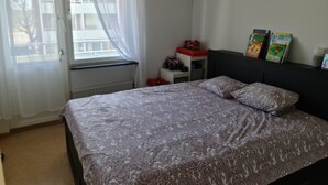 A bedroom with a bed, a window with curtains, a radiator, a shelf with toys, and books on the wall. - 2 Bedroomapartment in Danderyd, City Stay (Danderyd)