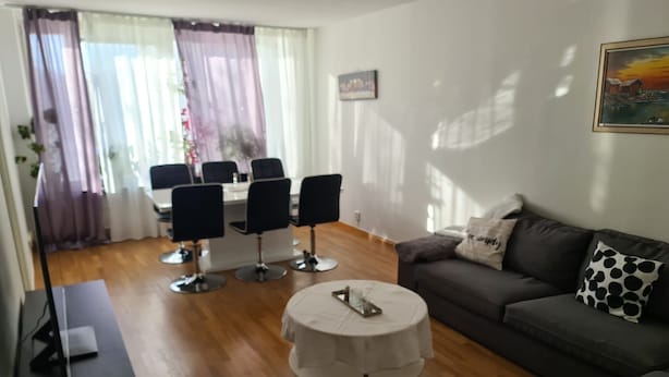 A living room with a sofa, a round coffee table, a TV stand, and a dining area with chairs and a table. - 2 Bedroomapartment in Danderyd, City Stay (Danderyd)