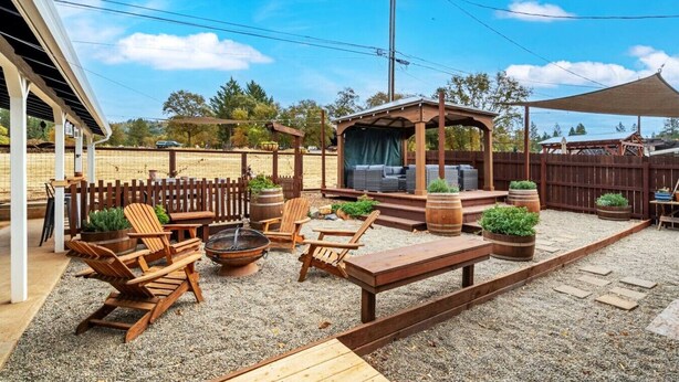 A covered outdoor seating area with wooden furniture, a fire pit, and planters. - Vintage Vine Retreat w/ Private Studio ~walk Dtwn! (Murphys)