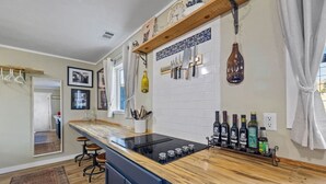 A kitchen with a wooden countertop, hanging knives, and wine bottles. - Vintage Vine Retreat w/ Private Studio ~walk Dtwn! (Murphys)
