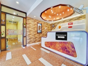 A reception area with a wooden wall, a clock, a sign reading 'TOWNHOUSE Company-Serviced', and a reception desk with a colorful design.
