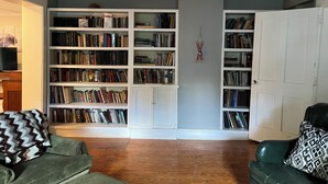 Ein Wohnzimmer mit einem grünen Sofa, einem Bücherregal und einer Tür.