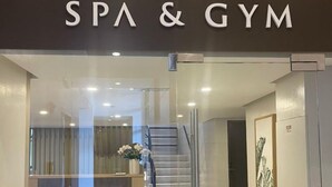 L’entrée du spa et de la salle de sport présente un design moderne, avec des portes en verre et un escalier menant à l’intérieur.