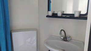 A compact bathroom with a toilet, sink, and mirror. - Quadruple hotel room (Lully)
