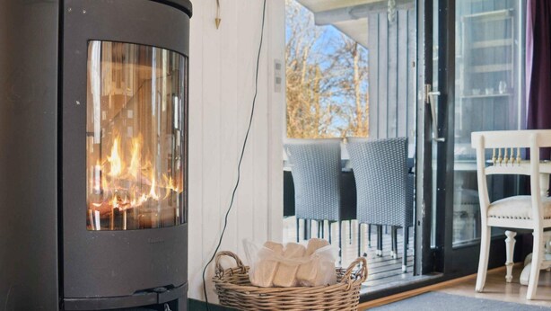 A wood-burning stove, wicker basket, and outdoor seating area with chairs. - 4 Star Holiday Home in Ronde (Ronde)