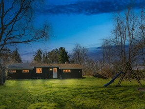 Ein Haus mit geneigtem Dach, einer Haustür und einer kleinen Veranda.