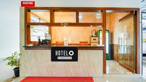 Ein Hotel-Empfangsbereich mit einer Rezeption, einem Schild mit der Aufschrift 'HOTELO Company-Serviced' und einem 'RECEPTION'-Schild darüber.