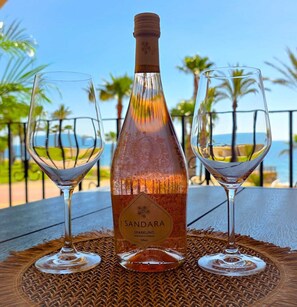 A bottle of Sandara sparkling wine on a table with two glasses, set against a coastal backdrop. - Unique by iulia (Oropesa del Mar)