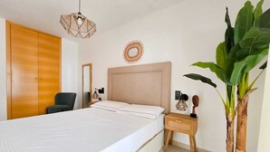 Ein Schlafzimmer mit Bett, Nachttisch, Lampe und einer großen Pflanze.
