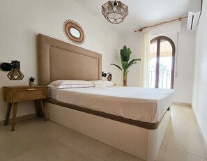 A bedroom with a bed, bedside table, lamp, wall decor, and a potted plant. - Unique by iulia (Oropesa del Mar)