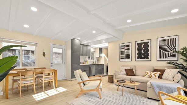 Een moderne woonkamer met een bank, stoelen, een eettafel en een keuken op de achtergrond.