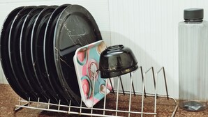 A metal rack holding stacked plates and a single teapot.