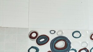 A shower head and a tiled wall with circular patterns.