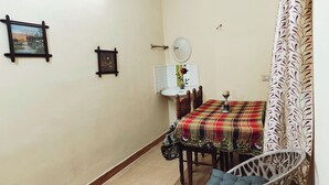 A small dining area with a table set for two, a white sink, and a mirror above it.