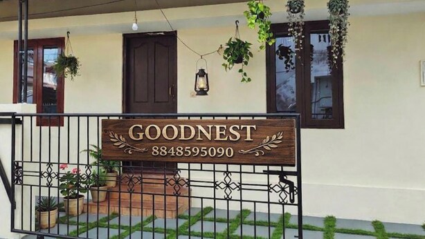 A house with a wooden sign reading 'GOODNEST' and a phone number.