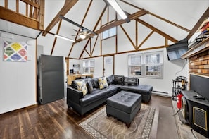 Una habitación estilo loft con vigas de madera a la vista, un sofá modular, chimenea y televisor.