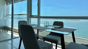 A modern room with a glass table and chairs, large windows, and a view of the sea. - Palmetto Sunset Ocean Front Cartagena Laguito 2903 (Cartagena)