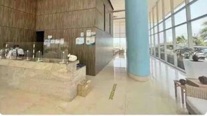 A lobby with a reception desk, wooden panel walls, a blue pillar, and large windows. - Palmetto Sunset Ocean Front Cartagena Laguito 2903 (Cartagena)