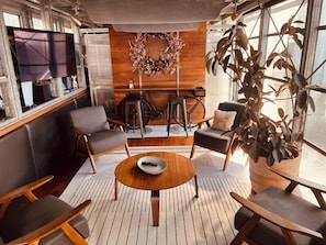 A cozy interior with a wooden wall, a round wooden table, and a large potted plant. - World Cup HQ: Dan Rockhill-Designed Luxury Apt, Lawrence's Coolest Neighborhood (Lawrence)