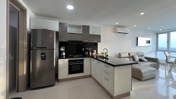 A modern kitchen with a built-in oven, a refrigerator, and a coffee machine. - Palmetto Sunset Ocean Front Cartagena Laguito 2904 (Cartagena)