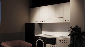A compact kitchen with a washing machine, microwave, and a chair. - The Rare Rooms by The Bloom - Saigon (Ho Chi Minh City)