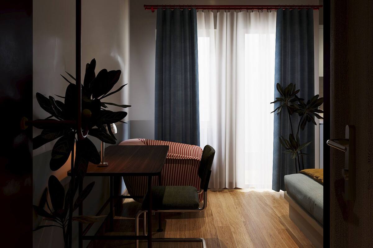A room with a dining table, chairs, a sofa, and two potted plants.